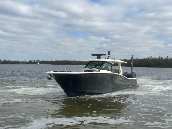  Yacht Photos Pics 2023 Scout 425 LXF boat cruising on a calm lake under cloudy skies.