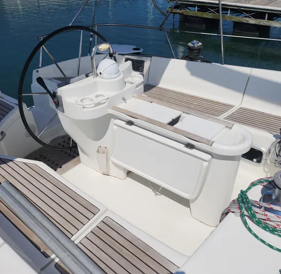 Scot-free Yacht Photos Pics 1999 Beneteau Oceanis 461 yacht cockpit with steering wheel and seating, docked by the water.