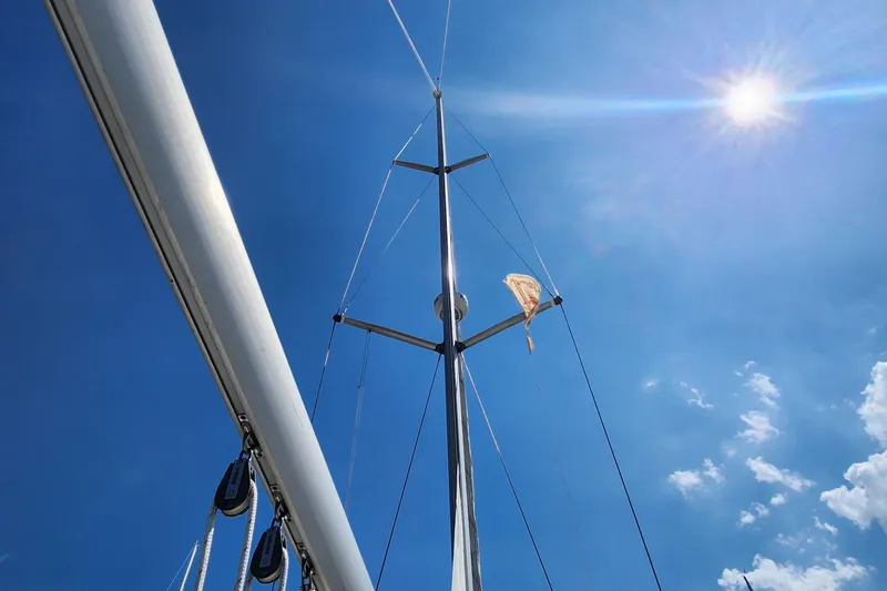 Scot-free Yacht Photos Pics Sailboat mast of 1999 Beneteau Oceanis 461 under bright sun and clear blue sky.