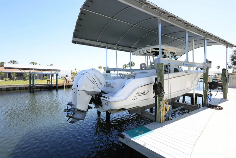  Yacht Photos Pics 2019 Boston Whaler 330 Outrage boat docked under a canopy on a sunny day.