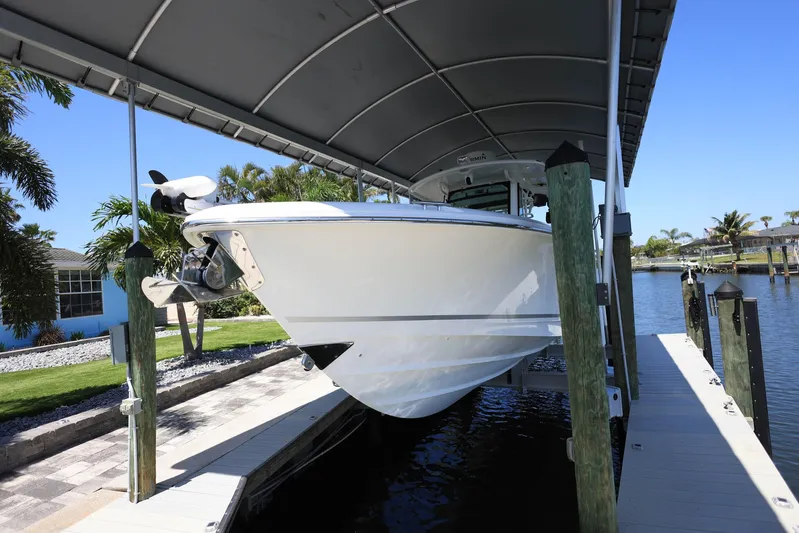  Yacht Photos Pics 2019 Boston Whaler 330 Outrage boat docked under a canopy, side view.