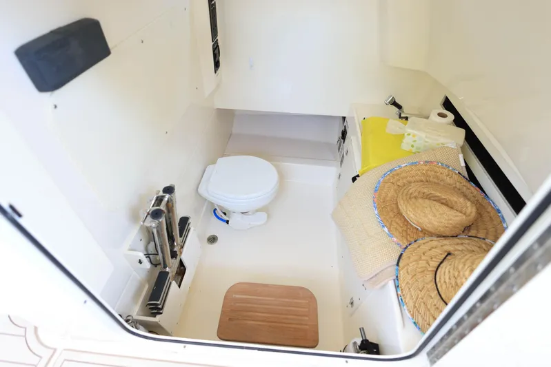  Yacht Photos Pics 2019 Boston Whaler 330 Outrage cabin interior with toilet, storage, and straw hats.