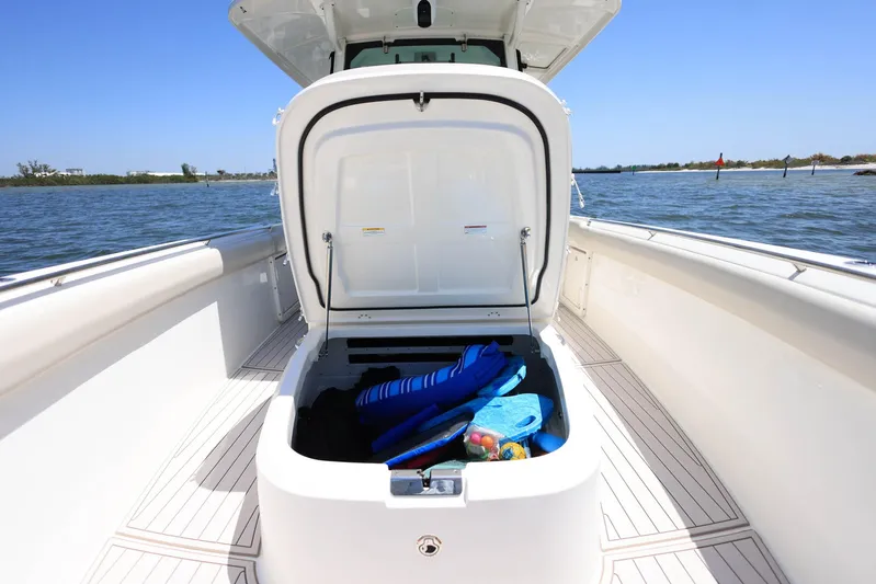  Yacht Photos Pics 2019 Boston Whaler 330 Outrage boat storage compartment open, revealing life jackets and gear.