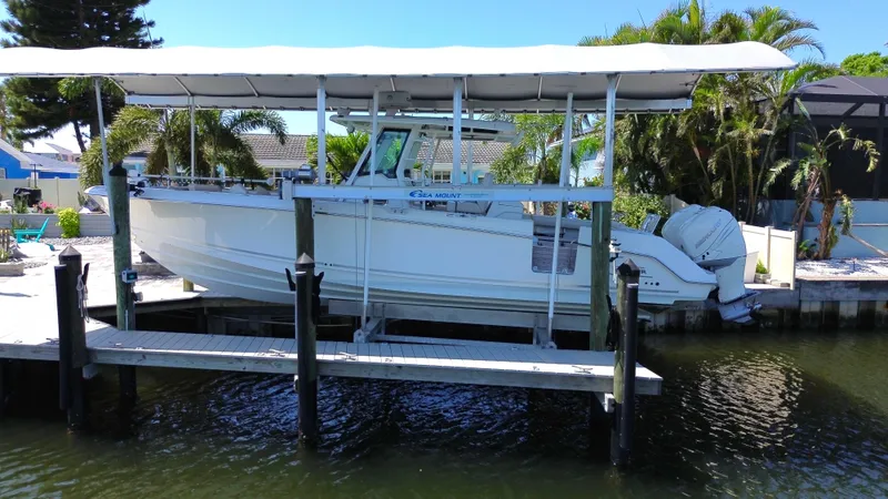  Yacht Photos Pics 2019 Boston Whaler 330 Outrage boat docked under a canopy near lush greenery.