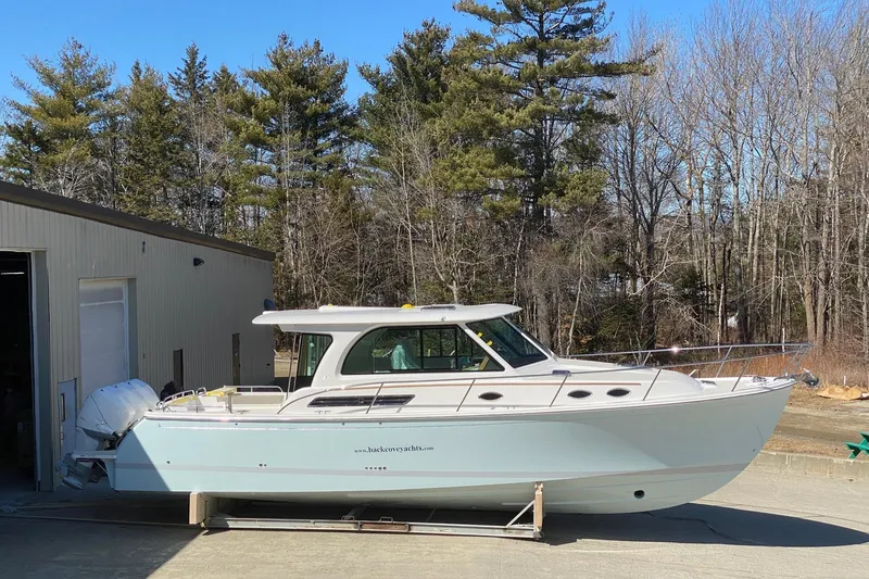American Girl Yacht Photos Pics 2021 Back Cove 390 boat parked outdoors near a building and trees.