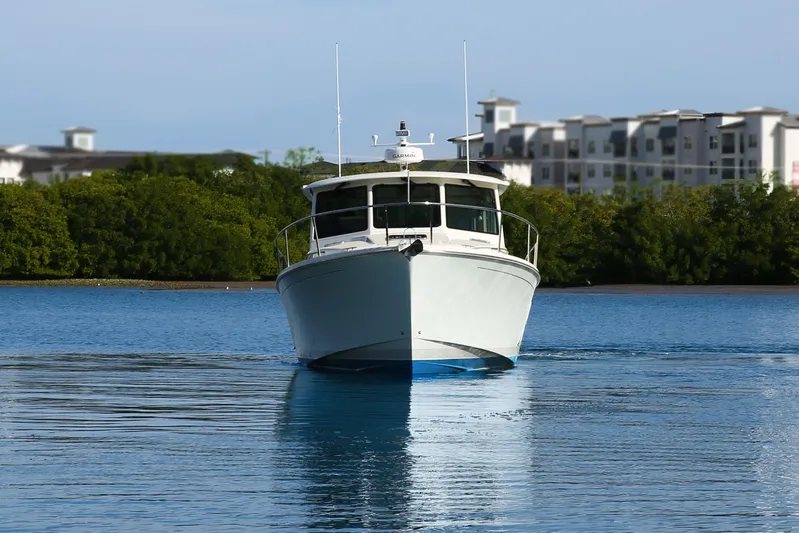American Girl Yacht Photos Pics 2021 Back Cove 390 boat on calm water with buildings in the background.