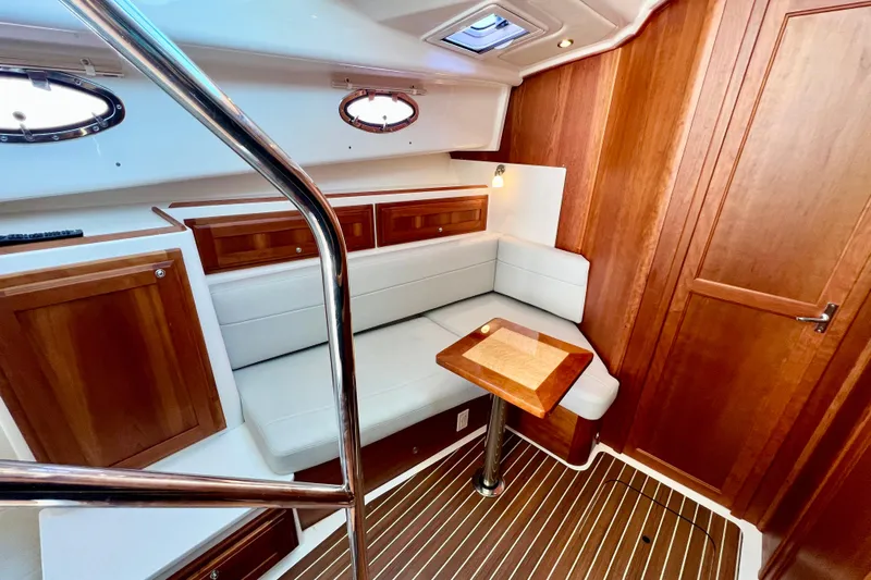 American Girl Yacht Photos Pics 2021 Back Cove 390 interior with wood paneling, white seating, and a small table.