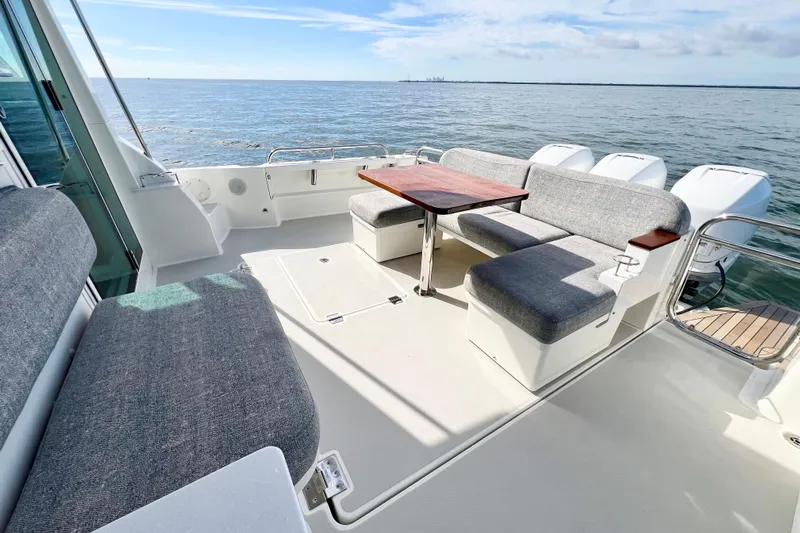 American Girl Yacht Photos Pics 2021 Back Cove 390 boat interior with seating and table, overlooking calm ocean waters.