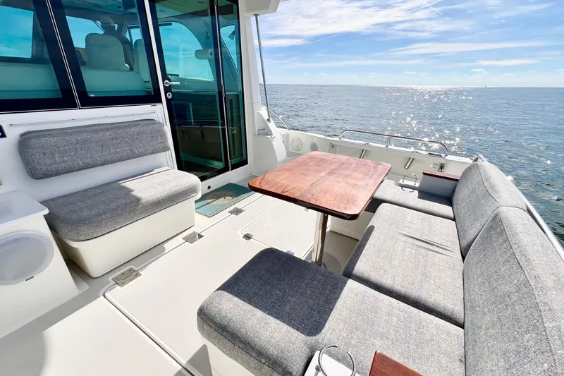 American Girl Yacht Photos Pics 2021 Back Cove 390 boat interior with gray seating and wooden table, ocean view.
