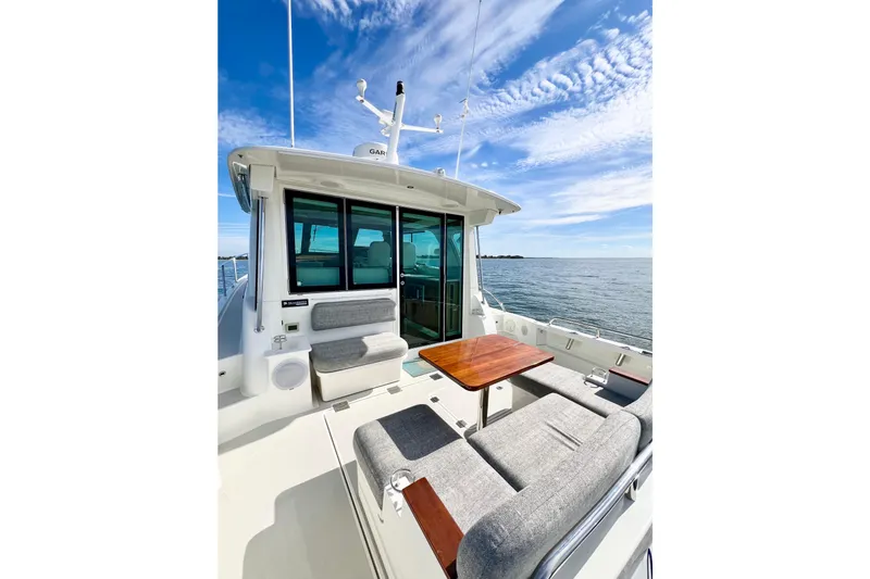 American Girl Yacht Photos Pics 2021 Back Cove 390 yacht deck with seating and table, ocean view, under blue sky.