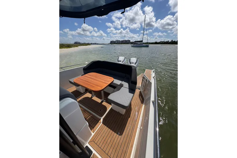  Yacht Photos Pics Nimbus T9 2021 boat with seating area, wooden table, and scenic waterfront view.