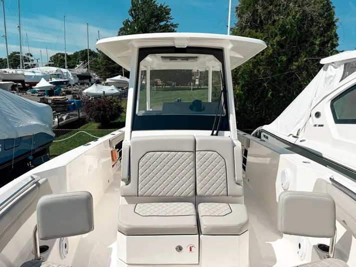  Yacht Photos Pics 2024 Pursuit S 288 Sport boat with cushioned seating and sleek design in a marina setting.