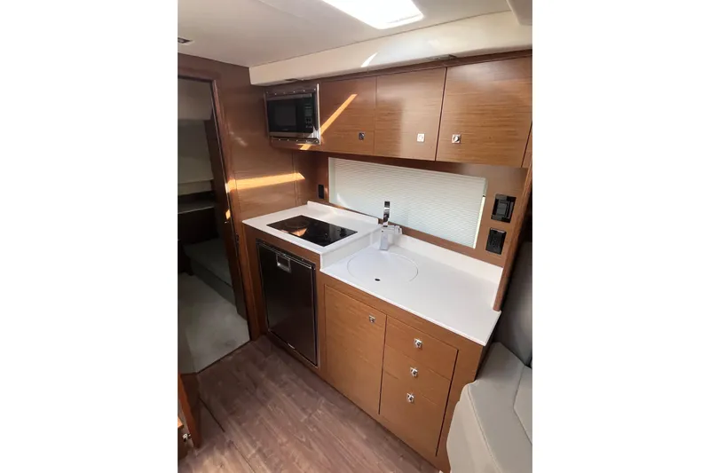  Yacht Photos Pics 2018 Cruisers Yachts 390 Express Coupe kitchen with modern appliances and wood cabinetry.
