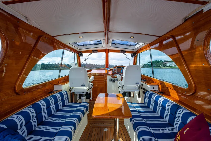 Miss Behave Yacht Photos Pics Luxurious interior of 2017 Hinckley Picnic Boat 37 MKIII with striped seating and wooden finishes.