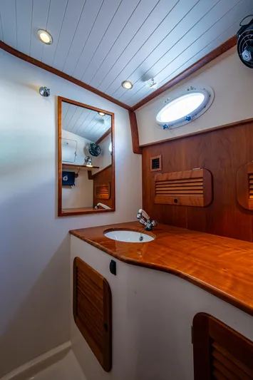 Miss Behave Yacht Photos Pics 2017 Hinckley Picnic Boat 37 MKIII bathroom with wooden cabinetry and round porthole.