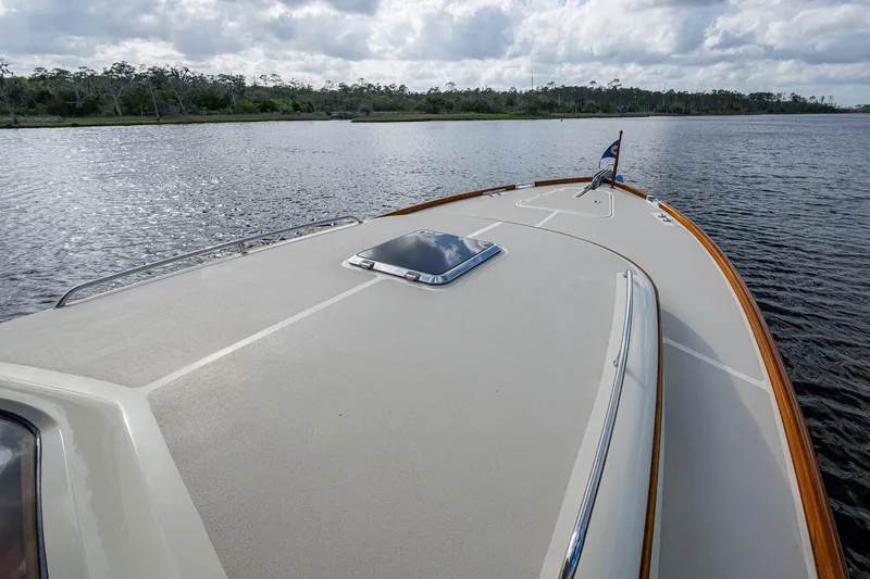 Miss Behave Yacht Photos Pics 2017 Hinckley Picnic Boat 37 MKIII cruising on a calm river under a cloudy sky.