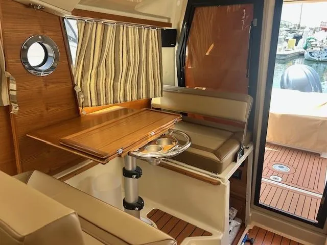  Yacht Photos Pics 2024 Ranger Luxury Edition boat interior with wooden table, beige seating, and striped curtains.