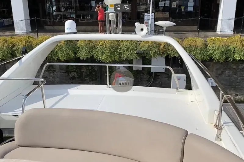 Bianca Lucida Yacht Photos Pics 1999 Azimut 58 yacht deck with seating, docked near greenery and a person in the background.