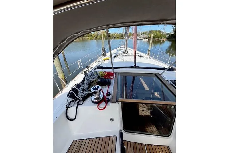 Rising Sun Yacht Photos Pics 2016 Jeanneau Sun Odyssey 50 DS sailboat deck with ropes and winch, docked by calm water.