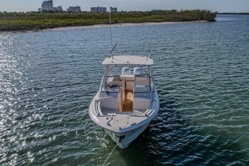 Fin & Tonic Yacht Photos Pics 2024 Grady-White Freedom 275 boat on water near shoreline, cityscape in background.