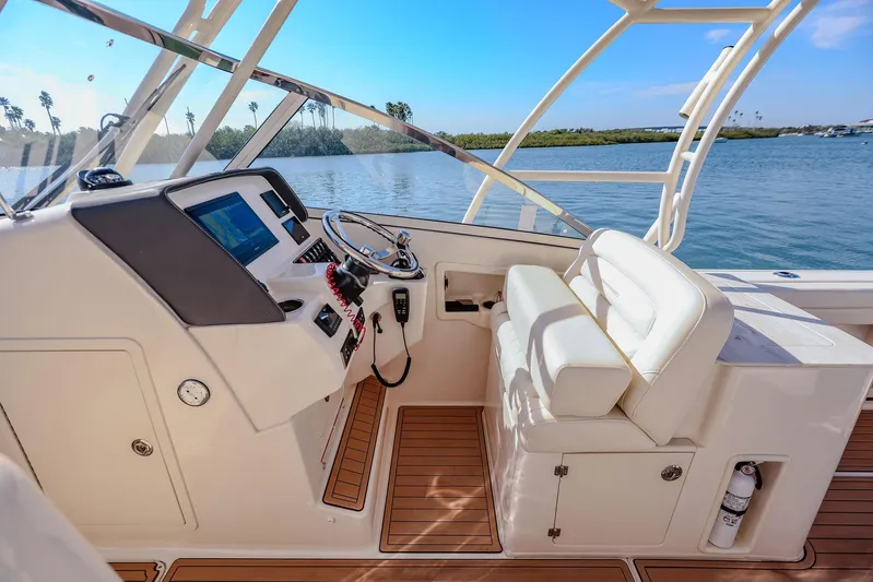 Fin & Tonic Yacht Photos Pics 2024 Grady-White Freedom 275 boat interior with helm, seating, and water view.