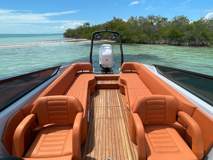 #0063 Bianca Panarea Yacht Photos Pics 2022 Cranchi 26 Rider boat with orange seating, docked near a scenic shoreline.