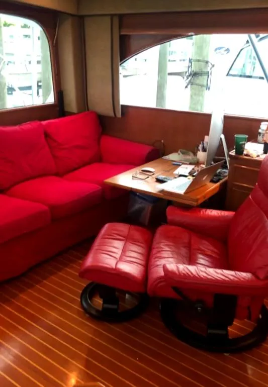 Luxurious red seating in a 1999 Post 50 yacht interior with wooden flooring.