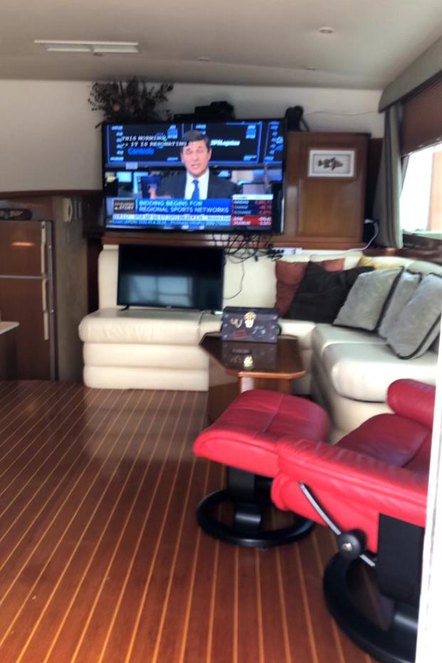 Luxurious yacht interior with leather seating, flat-screen TV, and wooden flooring, Post 50 model, 1999.