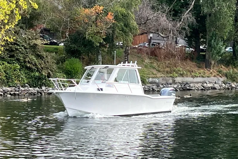  Yacht Photos Pics 2024 NorthCoast 285HT boat cruising on a scenic river with lush greenery.