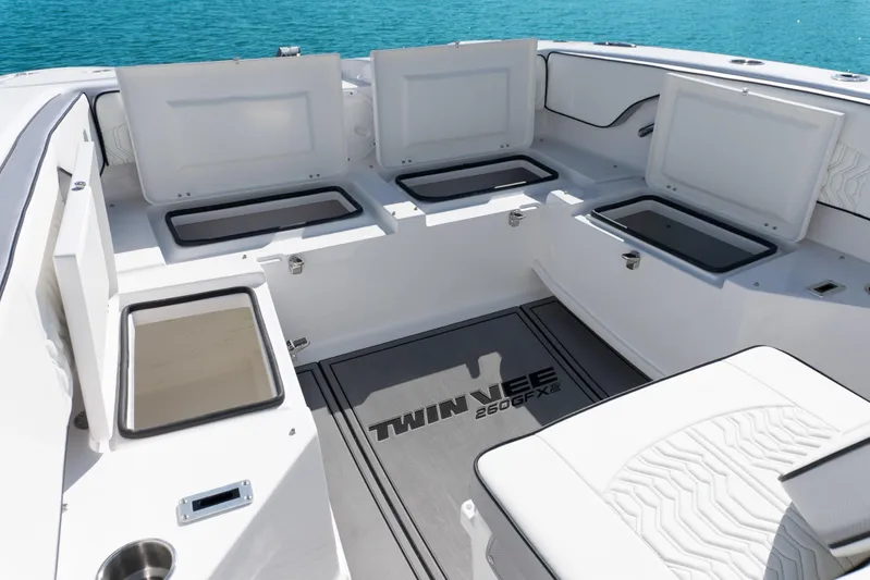  Yacht Photos Pics 2025 Twin Vee 260 GFX2 CC boat interior with open storage compartments, white seating, and ocean backdrop.