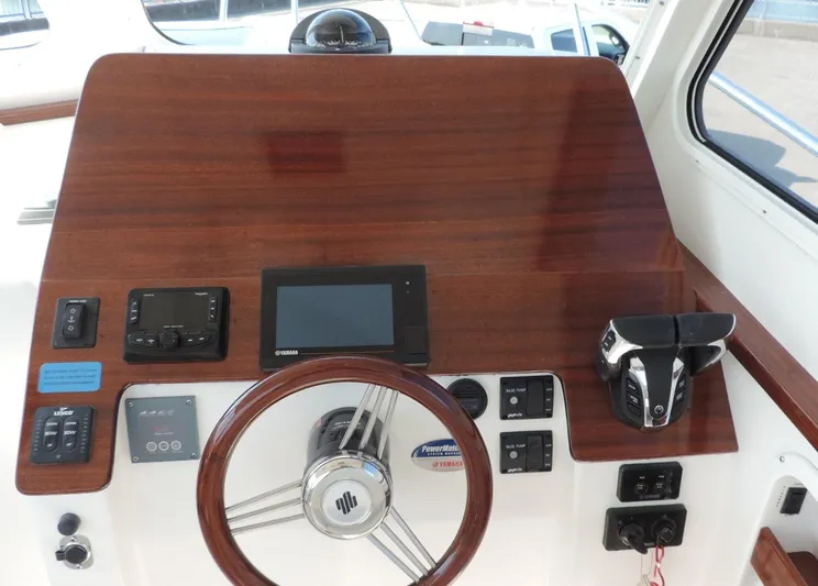  Yacht Photos Pics 2024 NorthCoast 285HT helm with wood finish, steering wheel, and electronic controls.