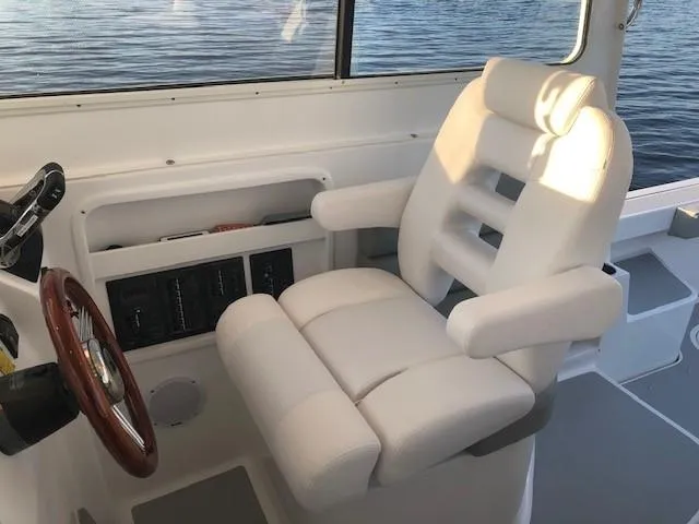  Yacht Photos Pics 2024 NorthCoast 285HT boat interior with white captain's chair and steering wheel.