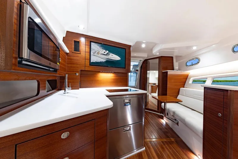  Yacht Photos Pics Manufacturer Provided Image: Luxurious interior of 2025 Pursuit OS 405 Offshore yacht with modern kitchen and seating area.