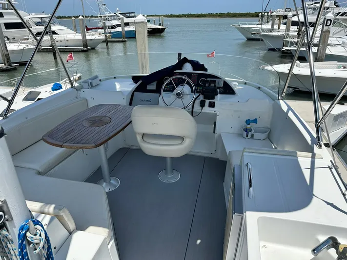 C'est Bon Yacht Photos Pics 2005 Beneteau Swift Trawler 42 cockpit with helm, seating, and table, docked at marina.