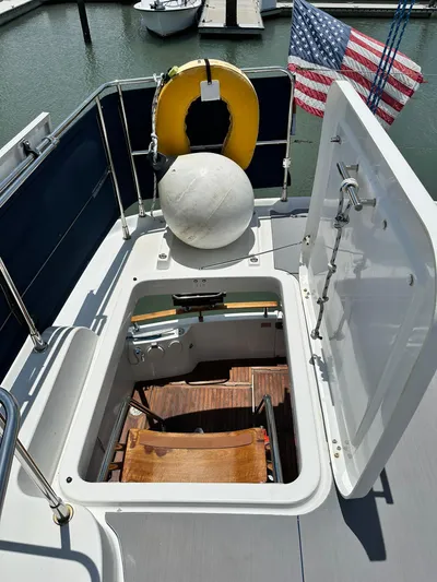 C'est Bon Yacht Photos Pics 2005 Beneteau Swift Trawler 42 deck with open hatch, life preserver, and American flag.