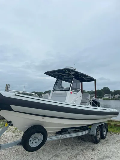  Yacht Photos Pics 2023 Protector 250 Chase boat on trailer by waterfront, overcast sky.