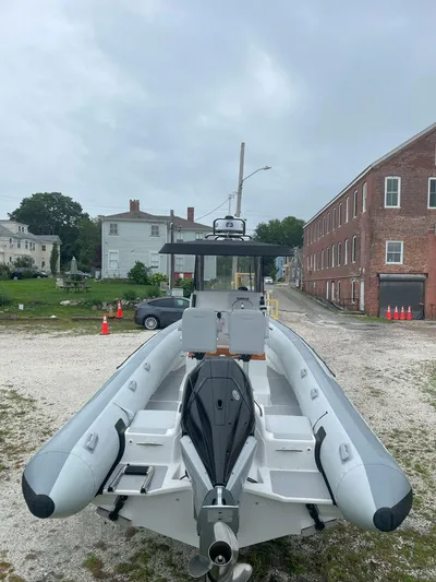  Yacht Photos Pics 2023 Protector 250 Chase boat on gravel lot, overcast sky, brick building background.