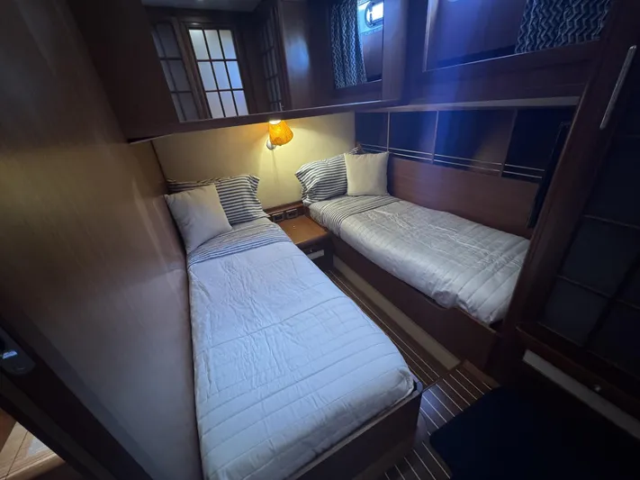 True Story Yacht Photos Pics Twin cabin interior of 2006 Mochi Craft 51' Dolphin yacht, featuring cozy beds and warm lighting.