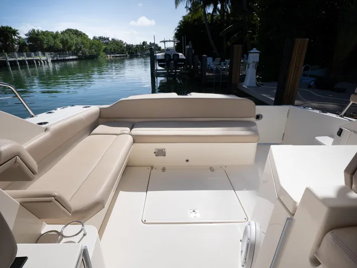 "nameless" Yacht Photos Pics 2014 Pursuit SC 365i Sport Coupe interior with beige seating, docked by a serene waterway.