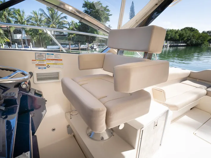 "nameless" Yacht Photos Pics Captain's chair on 2014 Pursuit SC 365i Sport Coupe, overlooking serene waters and lush greenery.