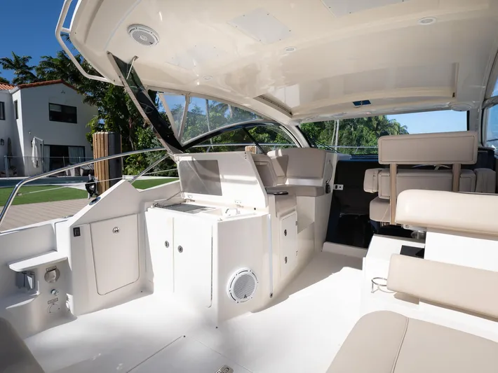 "nameless" Yacht Photos Pics 2014 Pursuit SC 365i Sport Coupe interior with seating and helm, docked near modern home.