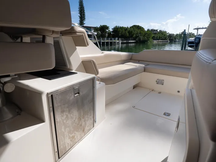 "nameless" Yacht Photos Pics 2014 Pursuit SC 365i Sport Coupe interior with seating and storage, docked by calm waters.
