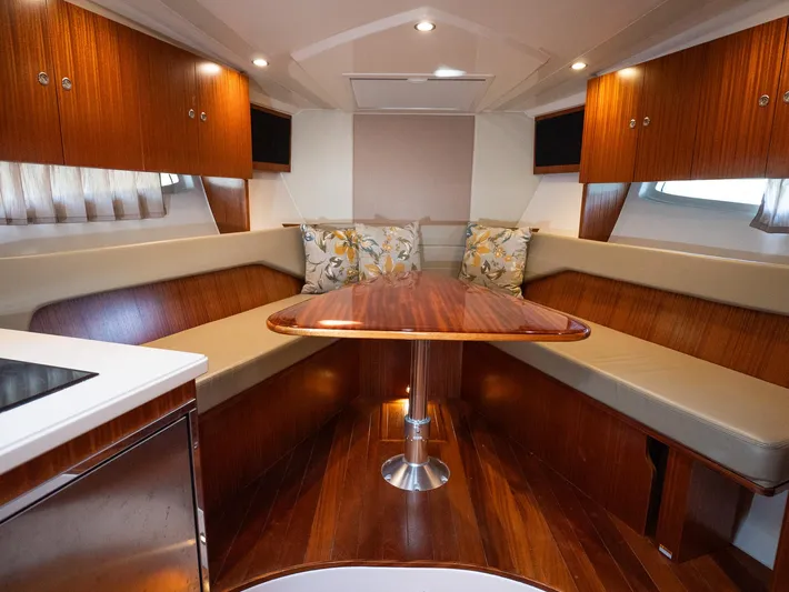 "nameless" Yacht Photos Pics 2014 Pursuit SC 365i Sport Coupe interior with wooden table and cushioned seating.