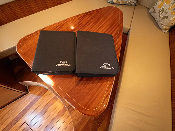 "nameless" Yacht Photos Pics Interior of 2014 Pursuit SC 365i Sport Coupe with wooden table and branded folders.