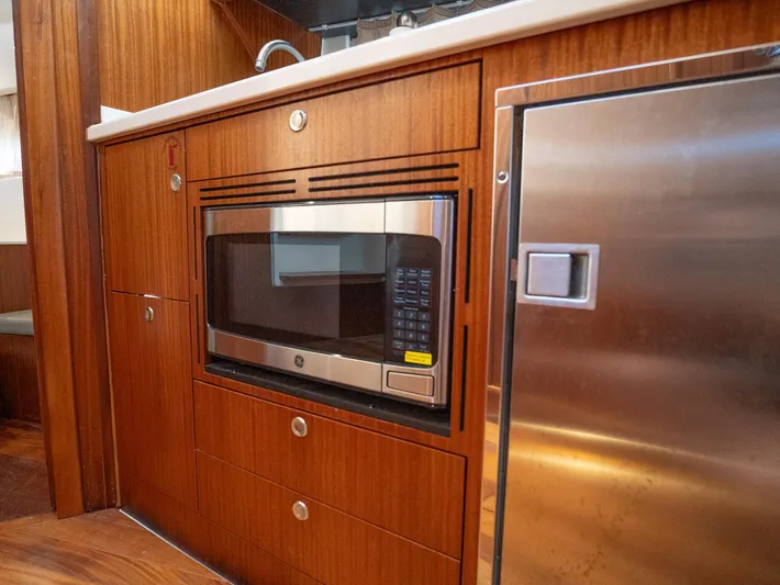 "nameless" Yacht Photos Pics 2014 Pursuit SC 365i Sport Coupe interior with microwave and stainless steel fridge.