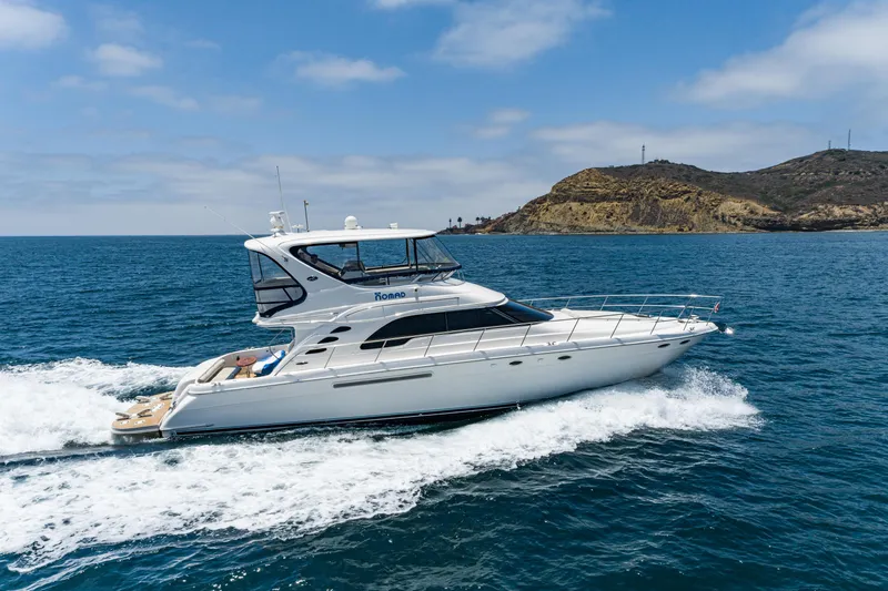 Blue Nomad Yacht Photos Pics 2001 Sea Ray 560 Sedan Bridge yacht cruising on open water near a rocky coastline.
