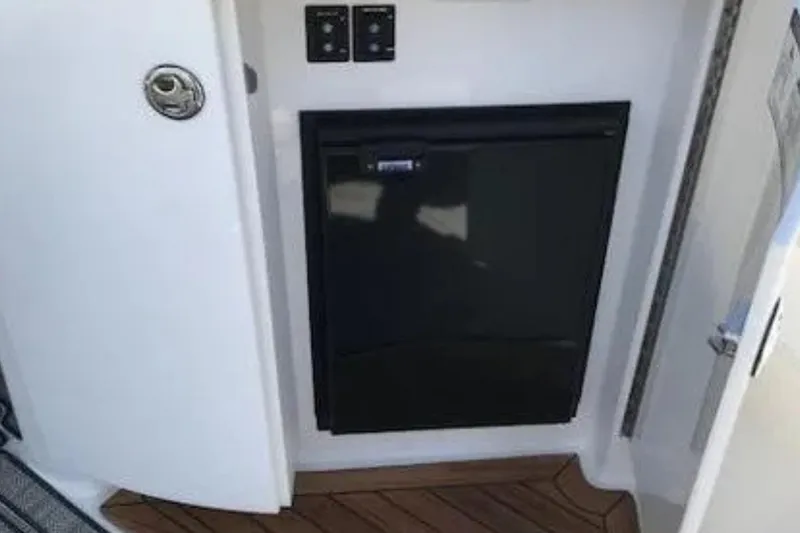  Yacht Photos Pics 2018 Cobalt R35 interior with compact black refrigerator and wooden flooring.