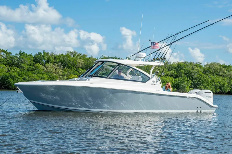  Yacht Photos Pics Manufacturer Provided Image: 2025 Pursuit DC 306 Dual Console boat on calm water, surrounded by lush greenery.
