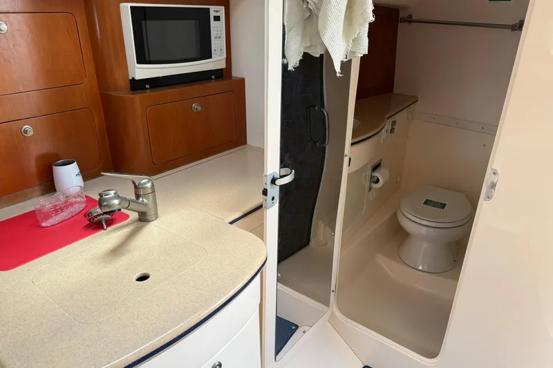  Yacht Photos Pics 2006 Intrepid 377 boat interior with kitchenette and bathroom, featuring a microwave and sink.