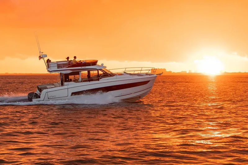  Yacht Photos Pics Manufacturer Provided Image: 2025 Jeanneau NC 1295 Fly yacht cruising at sunset on vibrant orange sea.